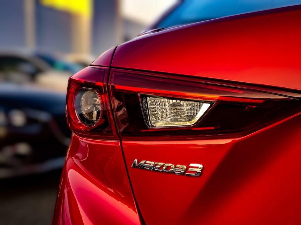 Stunning close-up of the tail light of a red Mazda 3 showcasing sleek design and vibrant color.