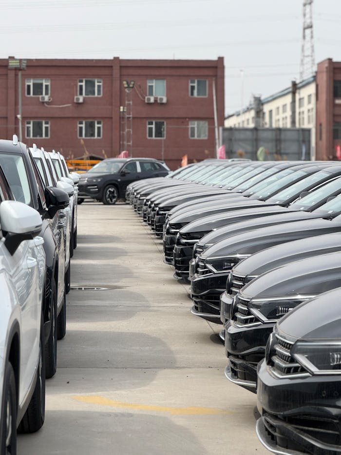 A view of modern cars neatly parked in an industrial lot on a cloudy day.