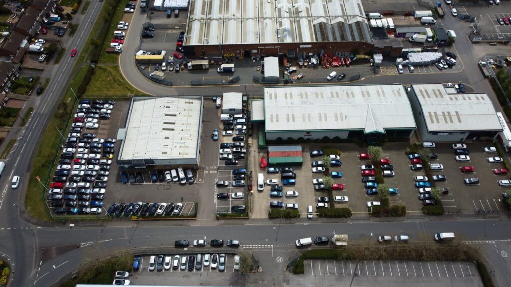 Drone shot capturing an industrial area with parking lots and buildings in Luton, England.