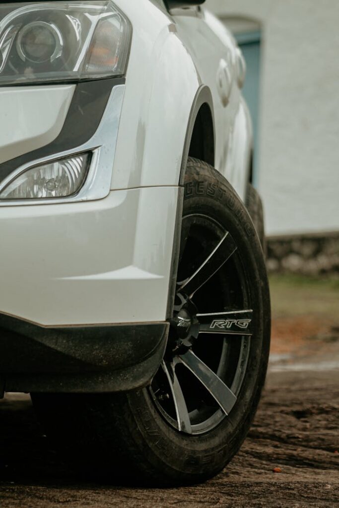 Detailed view of a car's front wheel and headlight, emphasizing design and chrome.
